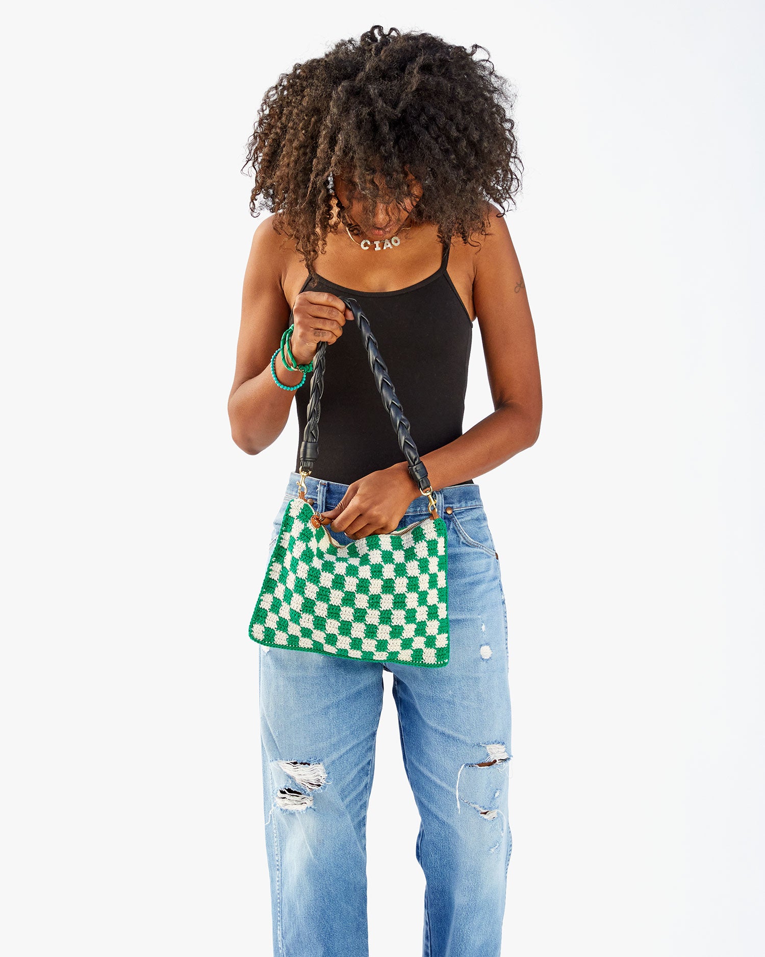 Mecca holding the Sea Green & Cream Crochet Checker Summer Flat Clutch with Tabs by the black braided leather shoulder strap