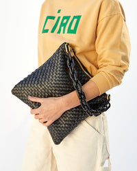danica holding the Black Woven Checker Foldover Clutch w/ Tabs with the black resin shorite strap attahed