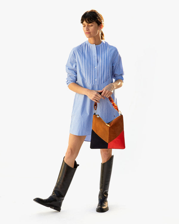 danica holding the Suede & Nappa Patchwork Foldover Clutch with Tabs by the tortoise resin shortie strap in front of her blue dress