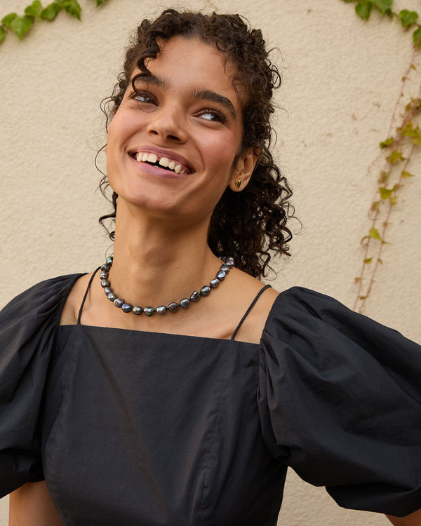 Haro wearing the Graphite Freshwater Pearl Necklace and smiling. 