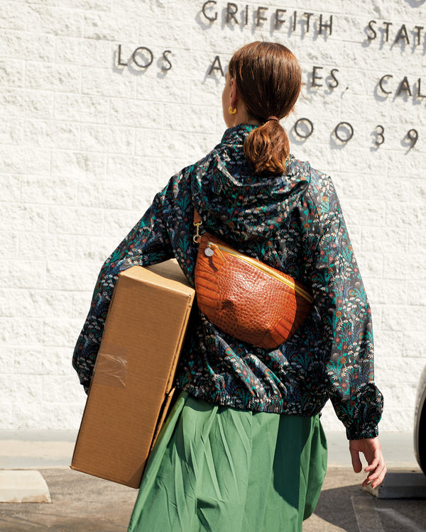 Lillian wearing the Cuoio Croco Grande Fanny on her back. she's facing away from the camera and she's carrying a box