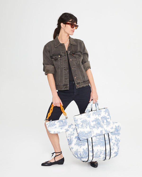 Danica carrying the St. Calais Blue Quilted Linen Toile Giant Trop Avion with Pochette and matching Laptop Case. She has our neon orange shortie resin strap attached to the Pochette.