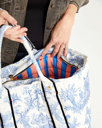 Danica opening the St. Calais Blue Quilted Linen Toile Giant Trop Avion and showing us the red and blue striped interior lining. 