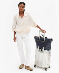 Grand Zip Sac in Twilight sits atop Vitoria's roller suitcase