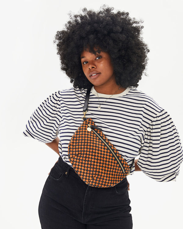 Candice wearing the Black & Natural Woven Checker Grande Fanny across her chest over the striped drop shoulder tee