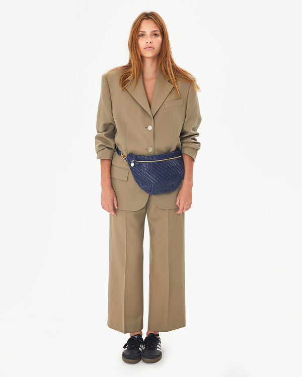 Aurelia wearing the Pacific Woven Zig Zag Grande Fanny around her waist in a tan suit with adidas sneakers