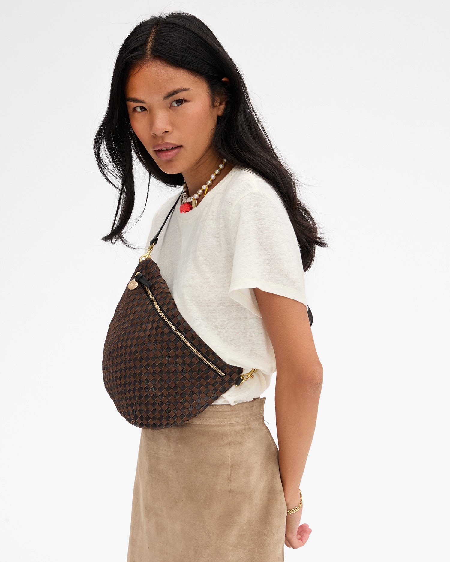 Close-up of model carrying the Black/Chocolate Woven Grande Fanny across her chest. 