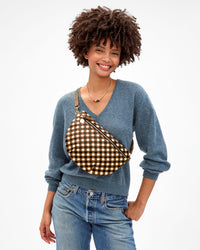 Model smiling and carrying the Oat Multi Diagonal Woven Grande Fanny across her chest. 