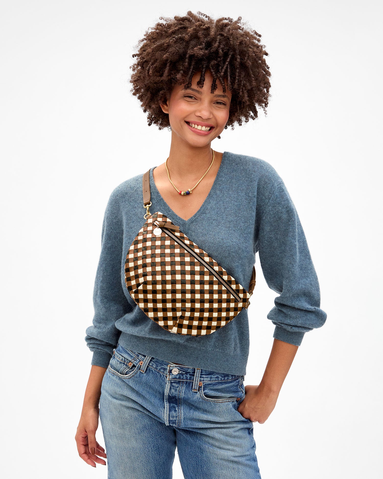 Model smiling and carrying the Oat Multi Diagonal Woven Grande Fanny across her chest. 