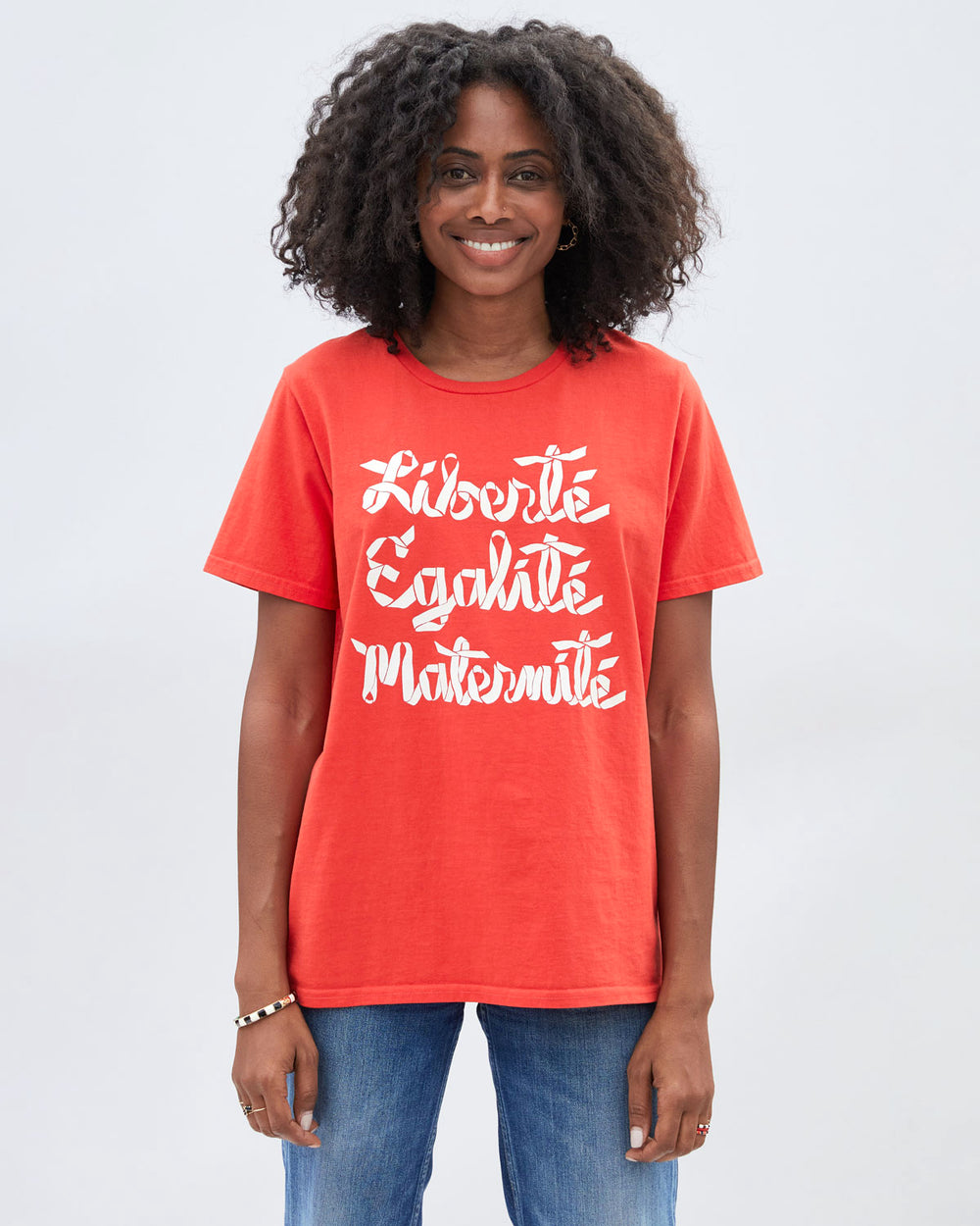 Mecca wearing the Poppy CV x EMC Liberté, Egalité, Maternité Heavy Tee untucked with denim jeans. 