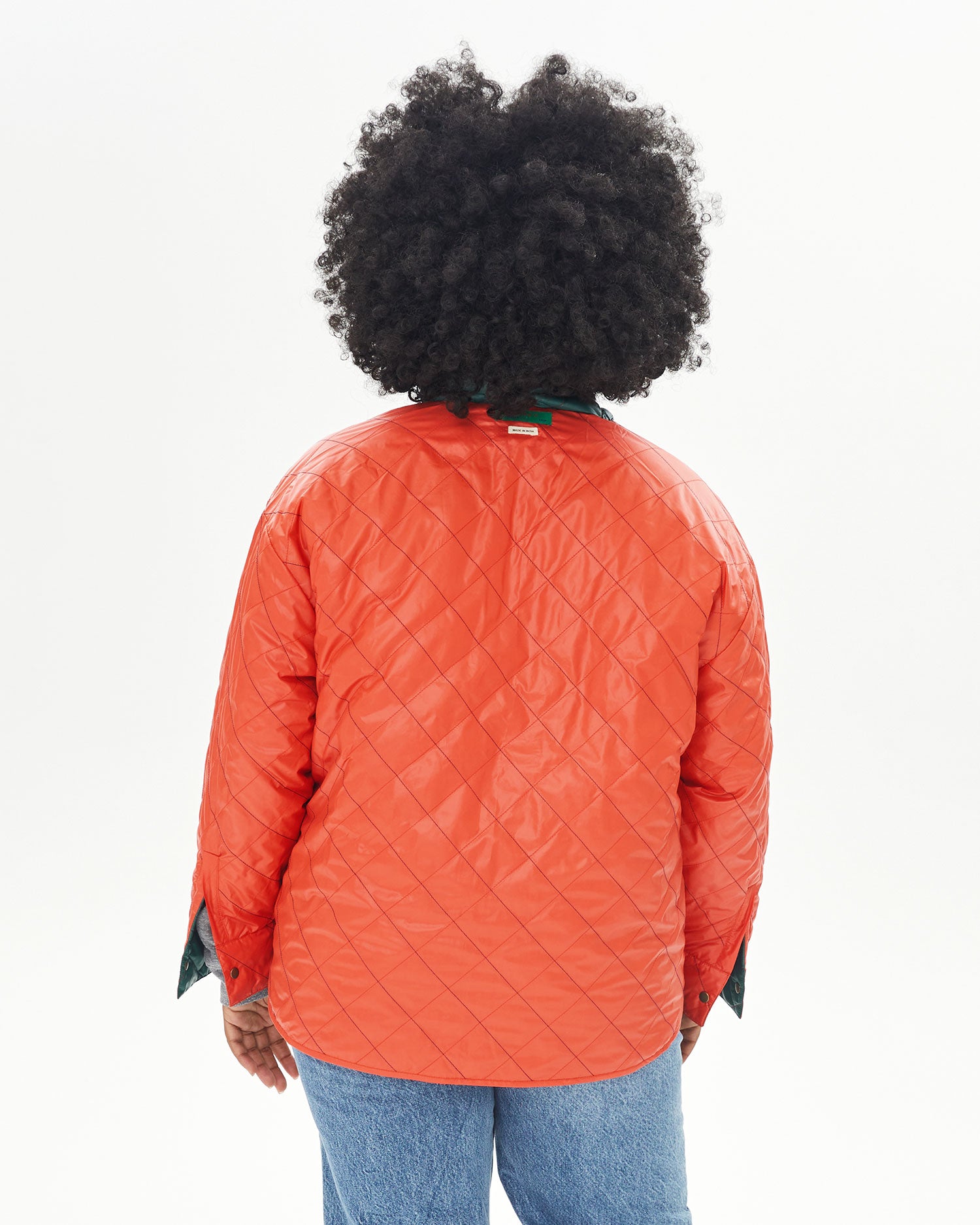 back view of Candice in the Spruce & Poppy Quilted Nylon Jacque Jacket with the poppy side facing outwards