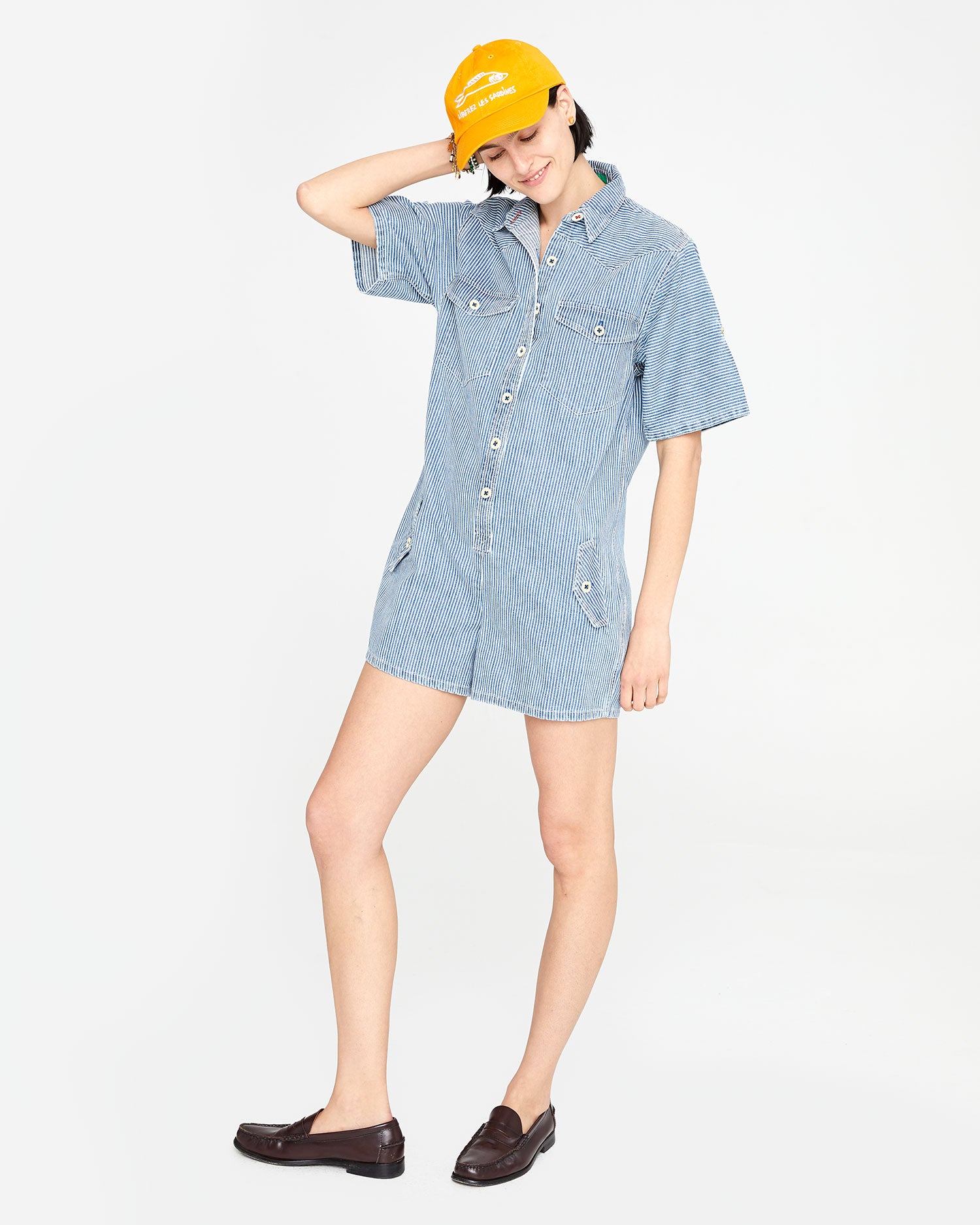 athena wearing the Engineer Stripe Jumpsuit Cargo with loafers and the marigold liberez les sardines baseball hat