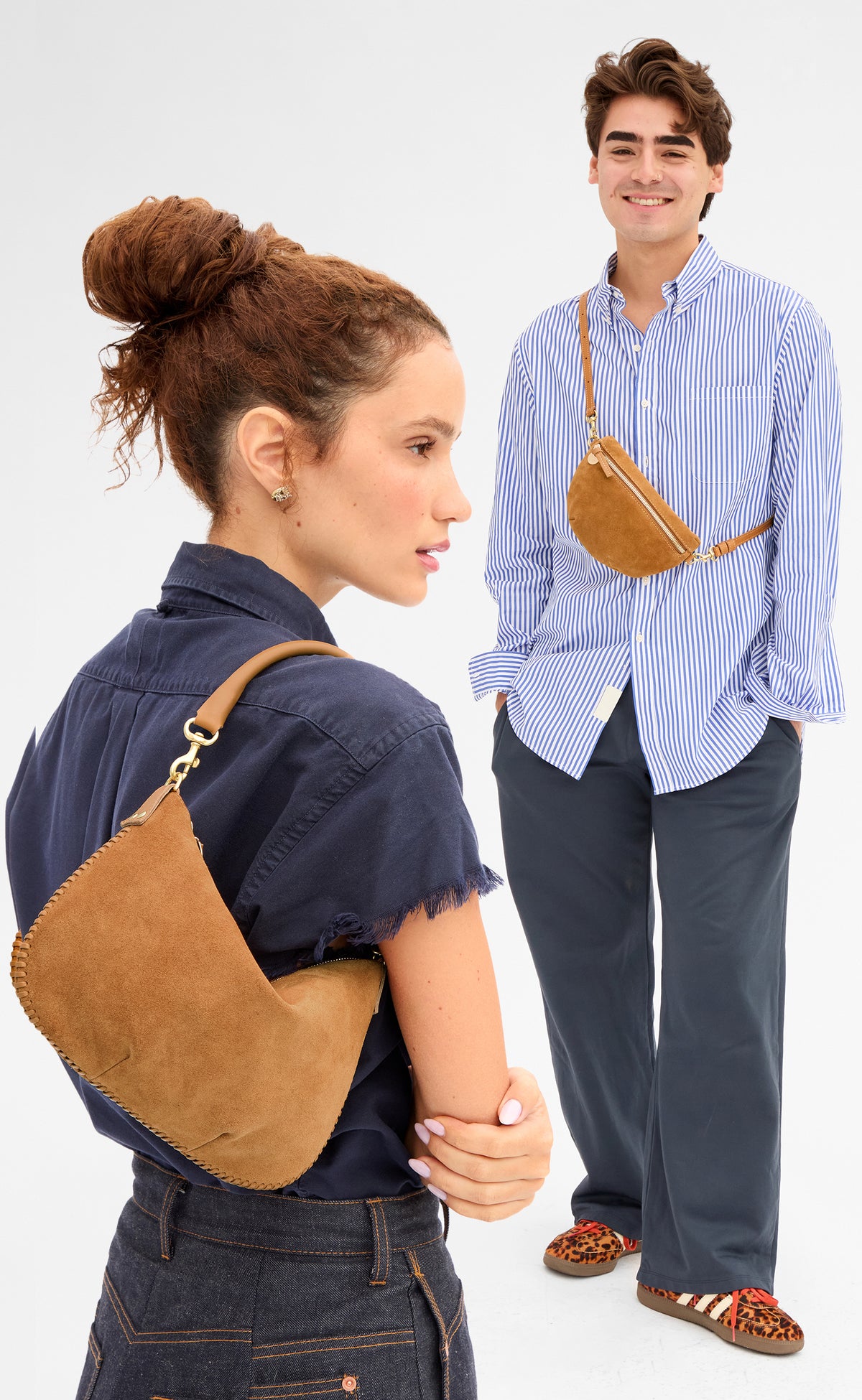 Woman carrying the Caramel Suede Petite Moyen and man carrying the Caramel Suede Petite Fanny across his chest. 
