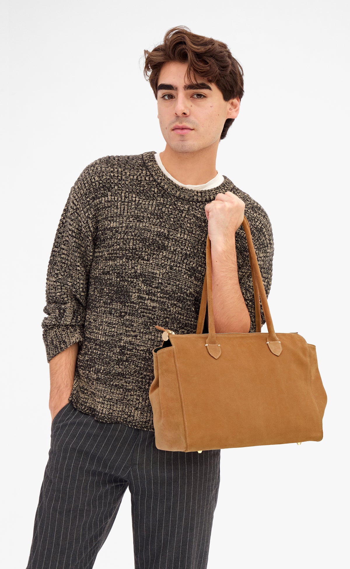 Male model carrying the Caramel Suede Beatrice by the top-handles. 