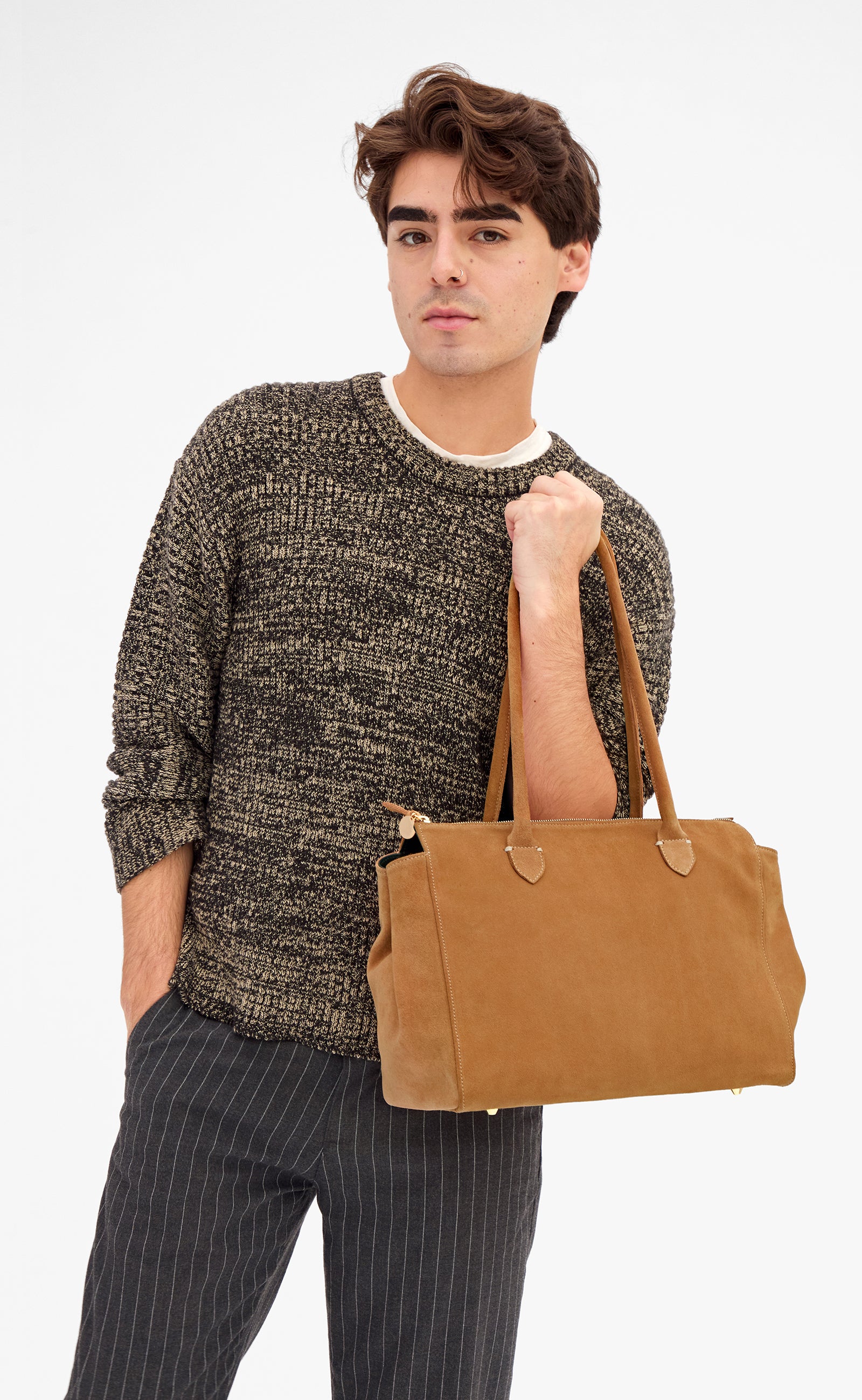 Male model carrying the Caramel Suede Beatrice by the top-handles. 