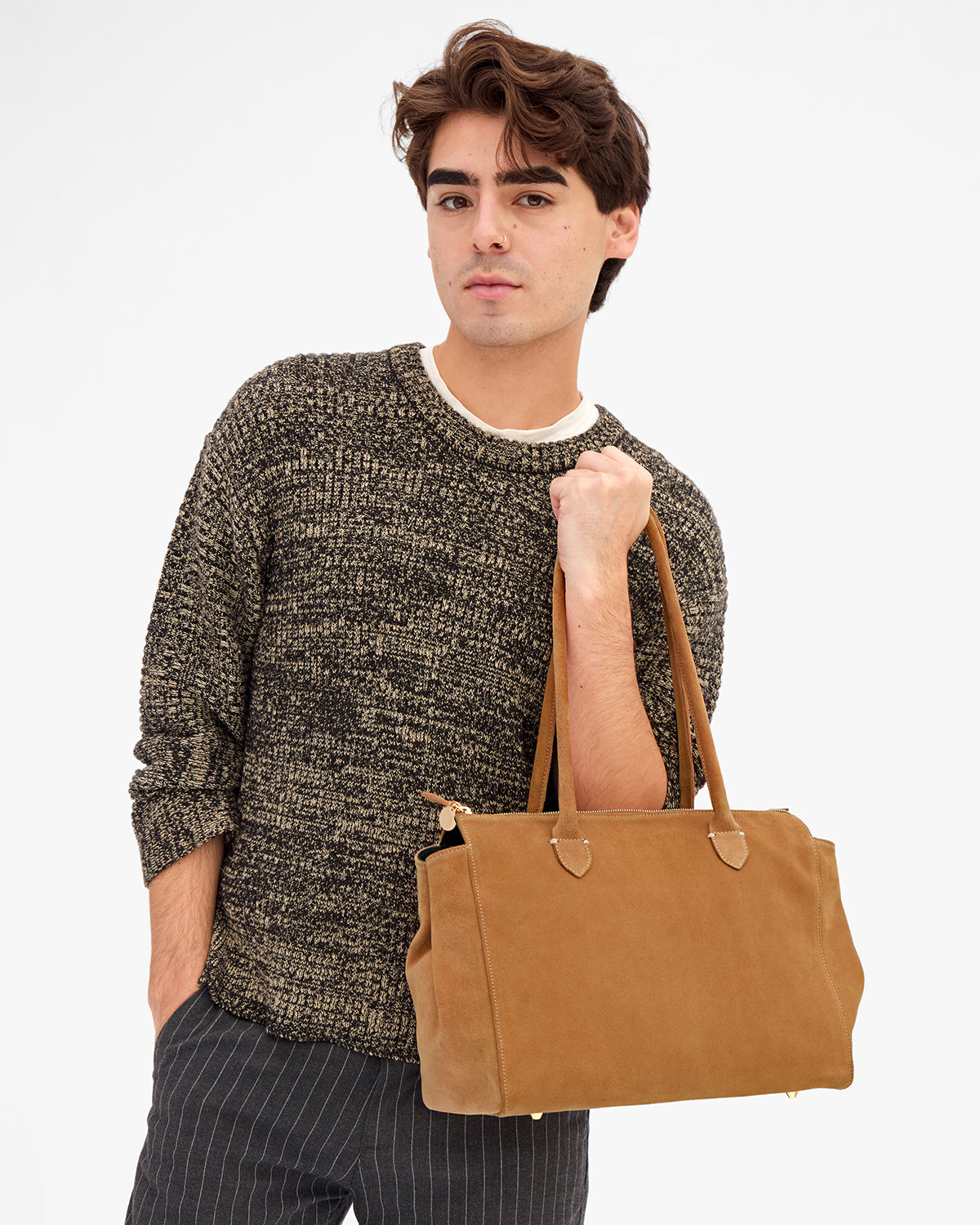 Male model carrying the Caramel Suede Beatrice by the top-handles. 