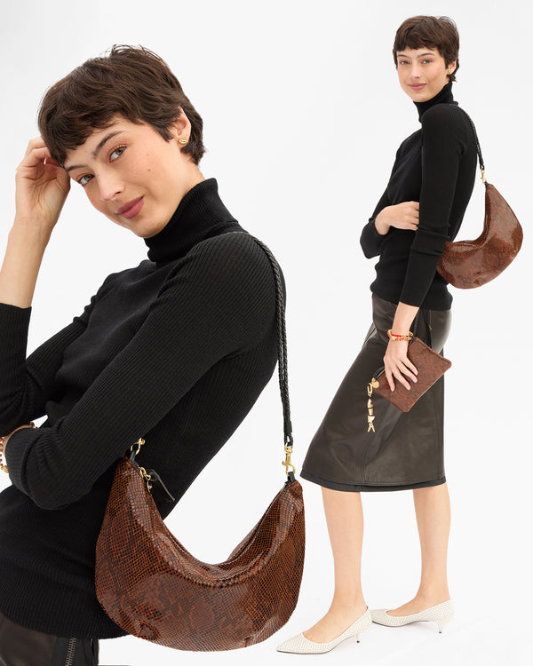 Model carrying the Auburn Embossed Python Lune and matching Wallet Clutch with Tabs. 