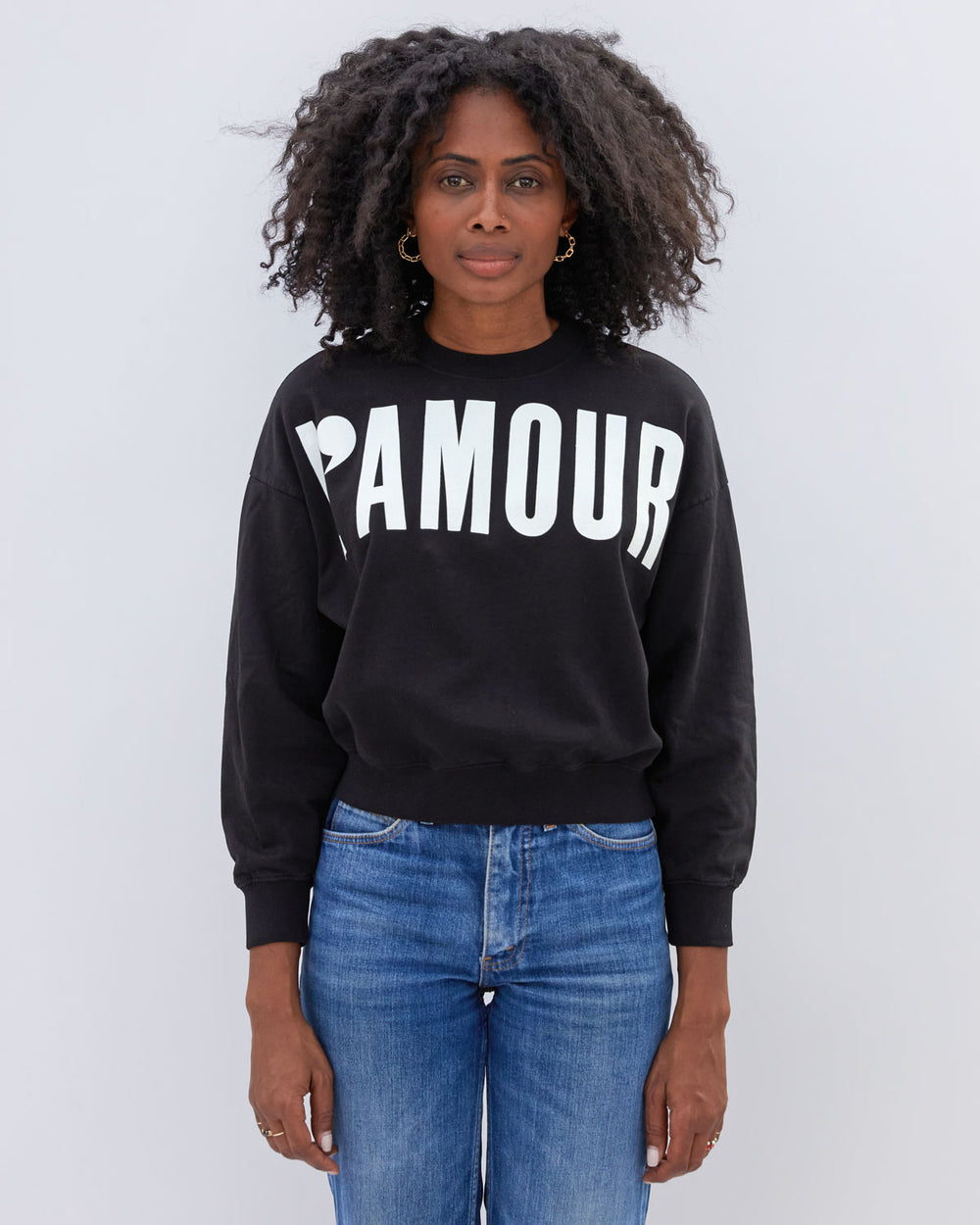 Mecca wearing the Black with Cream L'Amour Le Drop Sweatshirt untucked with jeans