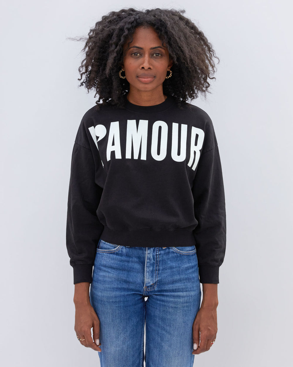 Mecca wearing the Black with Cream L'Amour Le Drop Sweatshirt untucked with jeans
