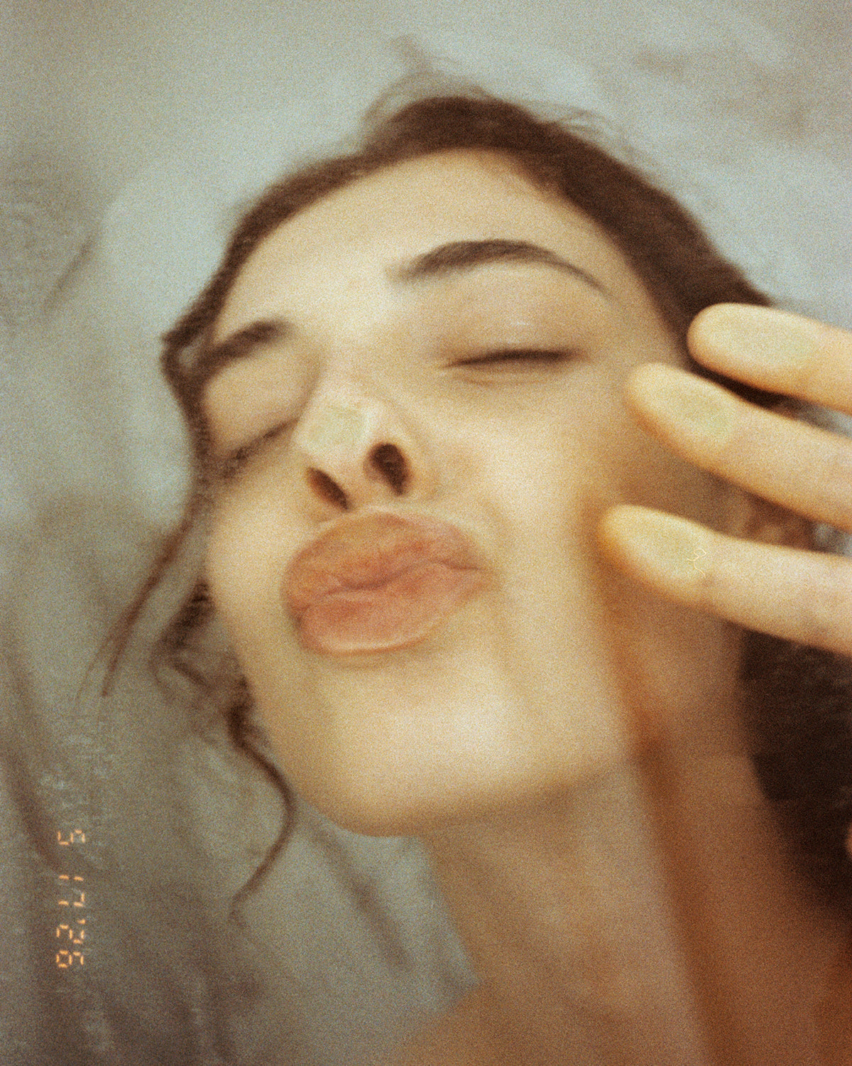 Photograph of a model kissing a translucent door. 
