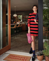 Zoe wearing the Black & Poppy Stripe Long Sleeve Dress holding the oven mitt and a napkin