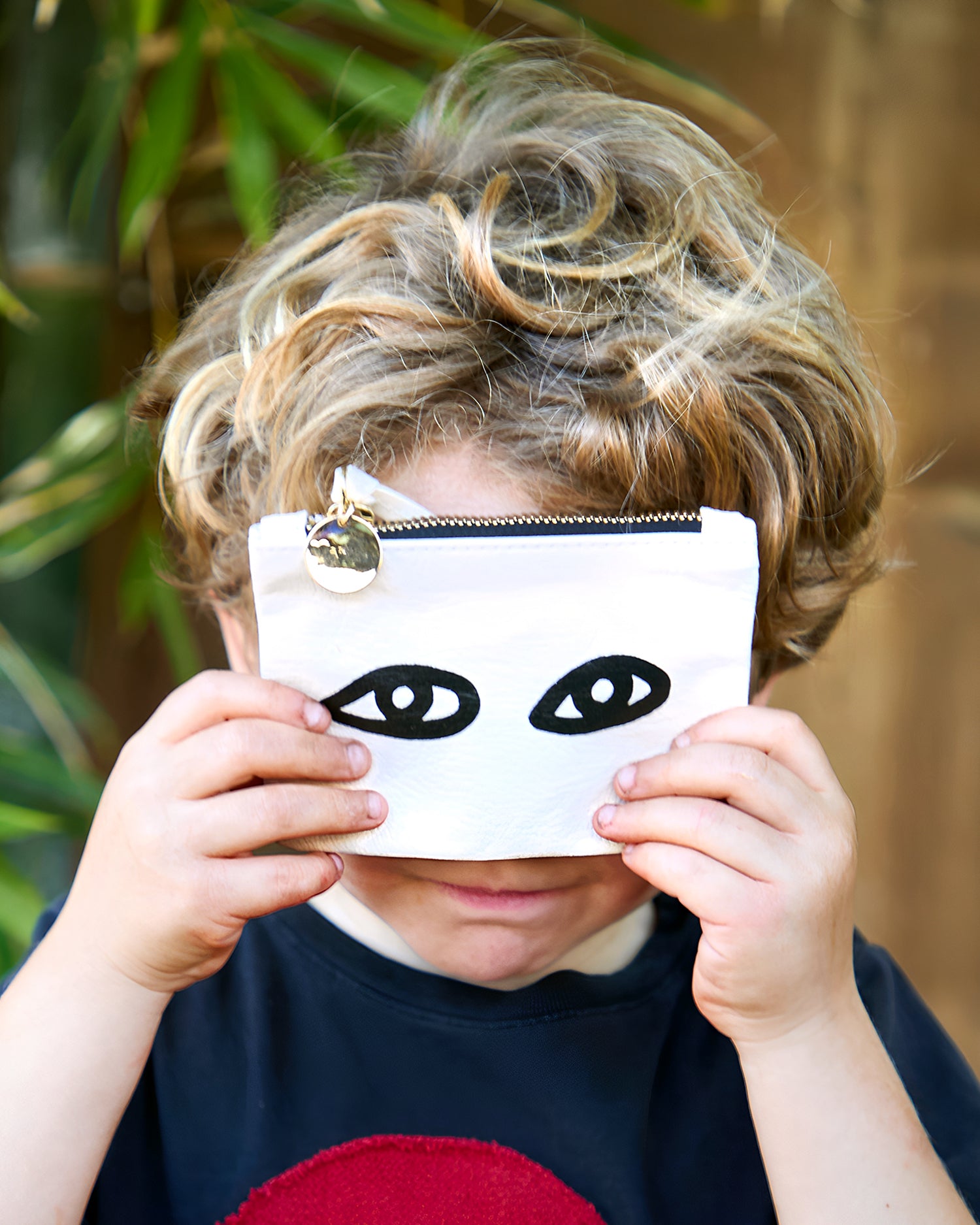 Child holding the Cream with Black Eyes Coin Clutch. 