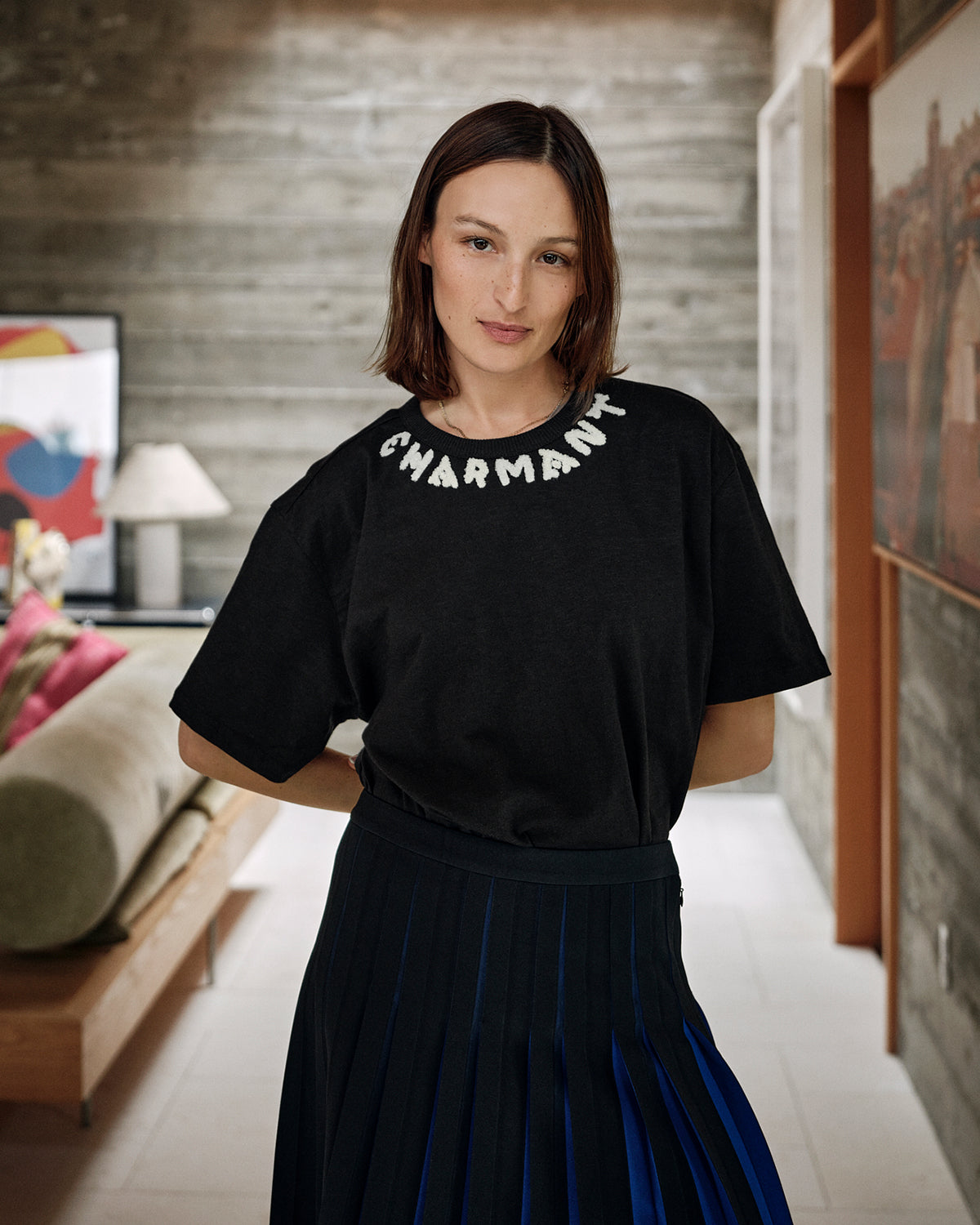 Zoe wearing the Black w/ Cream Charmant Tee tucked in to the pleated skirt.