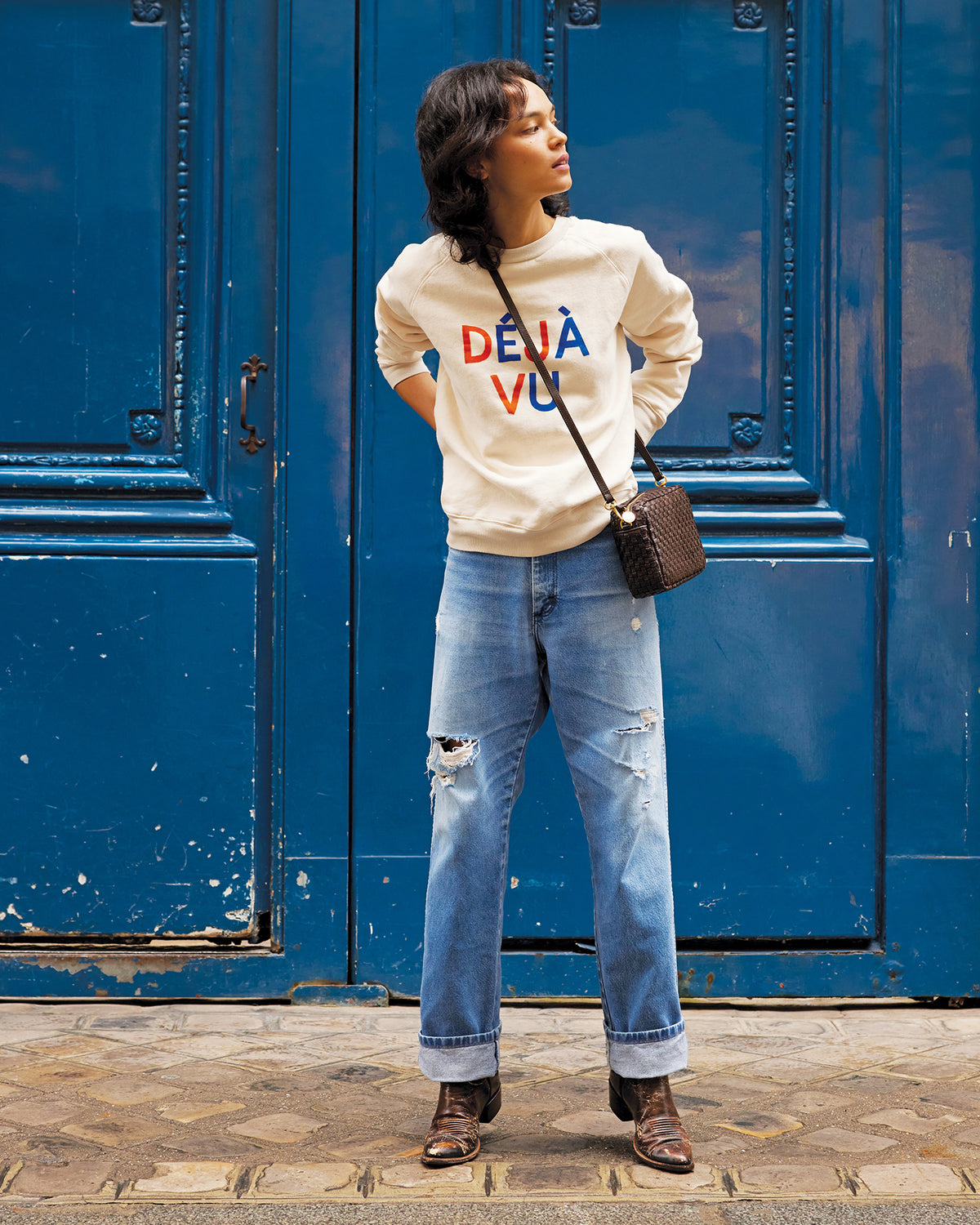Model wearing the Déjà Vu Sweatshirt with jeans and carrying the Kalamata Midi Sac as a crossbody bag.