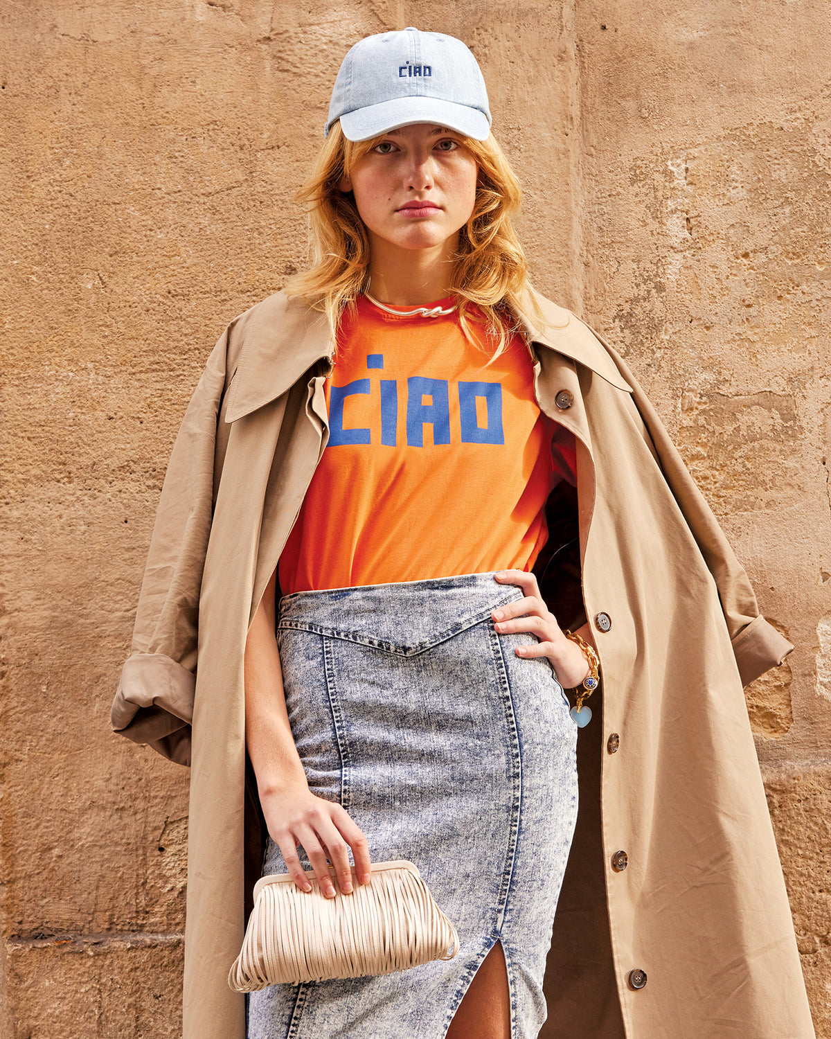 Model wearing the Light Denim Ciao Baseball Hat and Zucca and Cobalt Ciao Original Tee and carrying the Cream Fran Fran. 