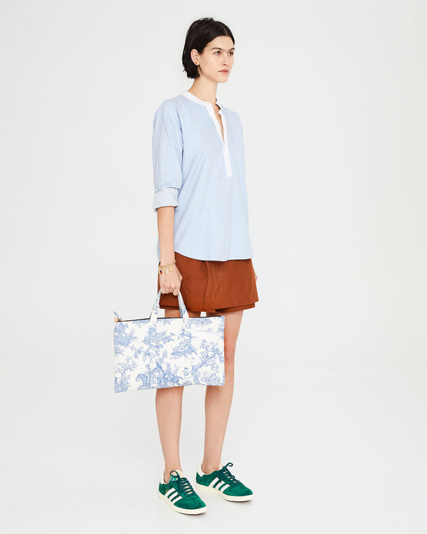 Athena carrying the St. Calais Blue Quilted Linen Toile Laptop Case by the top handle. 