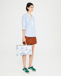 Athena carrying the St. Calais Blue Quilted Linen Toile Laptop Case by the top handle. 