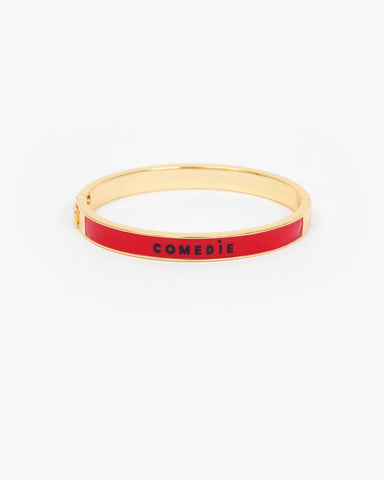 Le Bangle Bracelet with a vibrant red enamel inlay and the word 'COMEDIE' printed in black on the front.