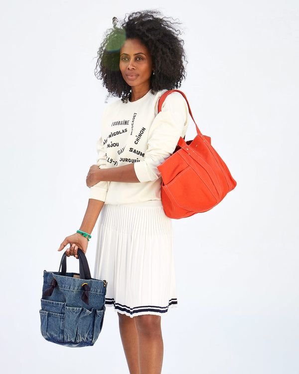Mecca holding both the Poppy Canvas Le Box Tote and the faded denim marine
