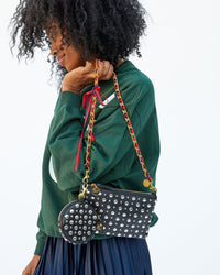 Mecca holding the black with silver studs Wallet Clutch with Tabs by the navy and red grosgrain ribbon chain strap 