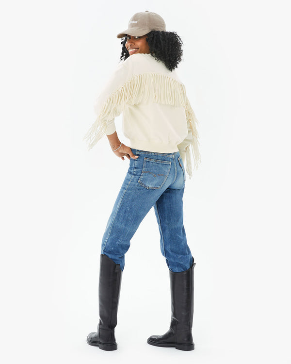 back view of mecca in the Cream Le Drop Fringe with jeans tucked into black riding boots