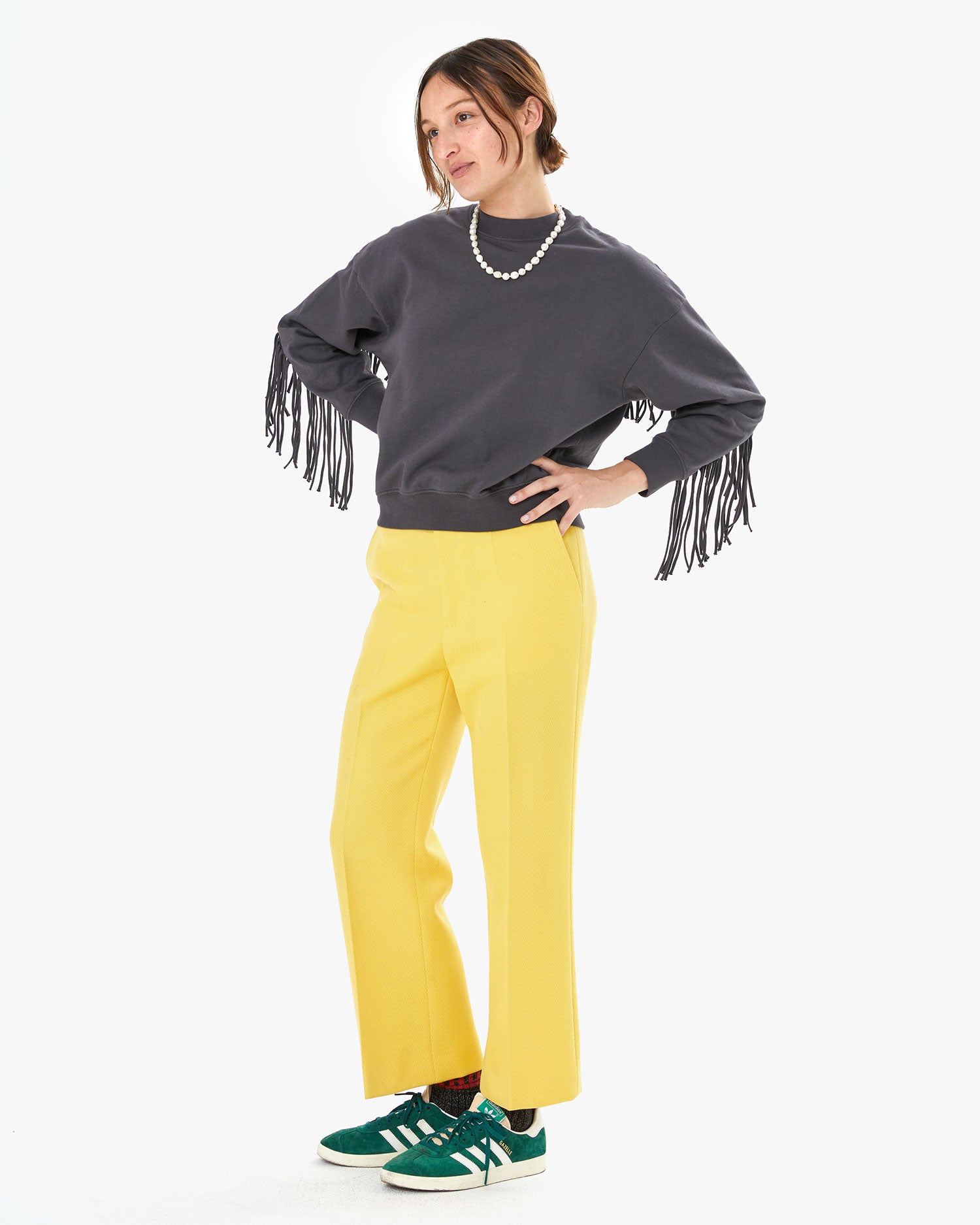 Zoe wearing the charcoal le drop fringe with yellow pants. She has her hands on her hips 