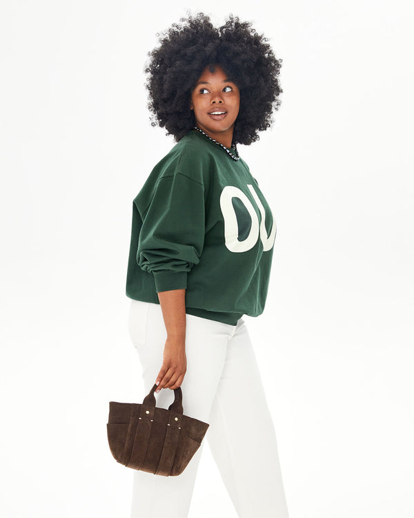 candice wearing a green sweatshirt and white pants with the Chocolate Suede Le Petit Box Tote by her side