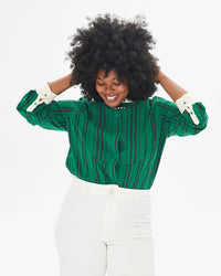 Candice smiling and touching her hair in the Green & Black Stripe Le Tux tucked in to white pants