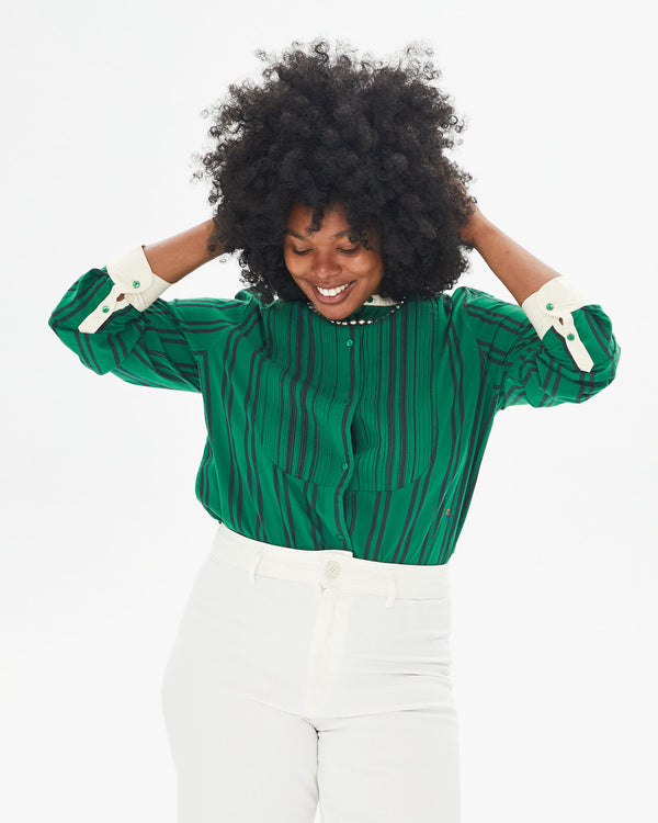 Candice smiling and touching her hair in the Green & Black Stripe Le Tux tucked in to white pants