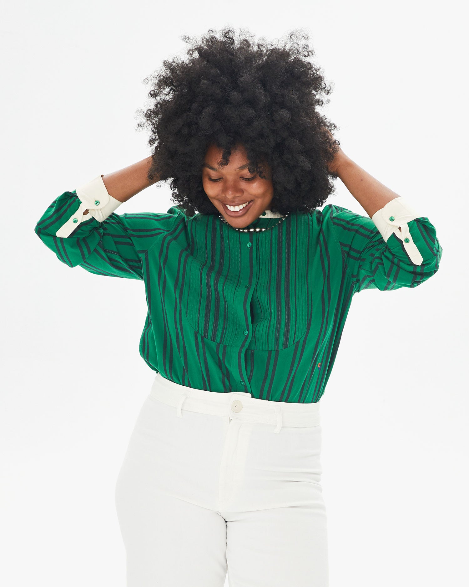 Candice smiling and touching her hair in the Green & Black Stripe Le Tux tucked in to white pants
