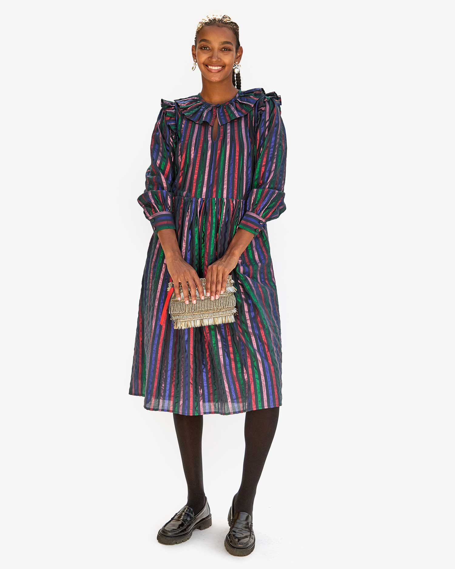 Jordan in the multi stripe leonie dress with loafers and tights. she's holding the Silver Beaded Fringe Estelle as a clutch
