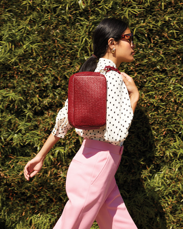 Sandra carrying the Oxblood Diagonal Woven Marisol on her shoulder by the oxblood shortie strap