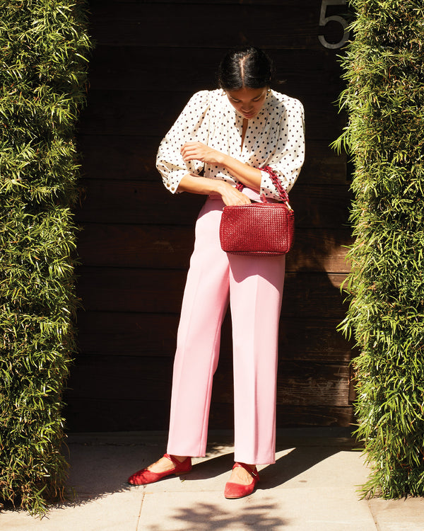 Sandra wearing pink pants and a polka dot shirt with the Oxblood Diagonal Woven Marisol on her forearm