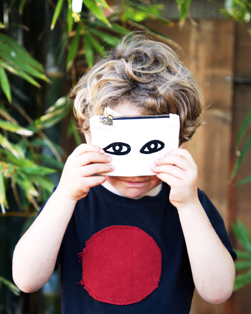 Child holding a Coin Clutch with Eyes. 