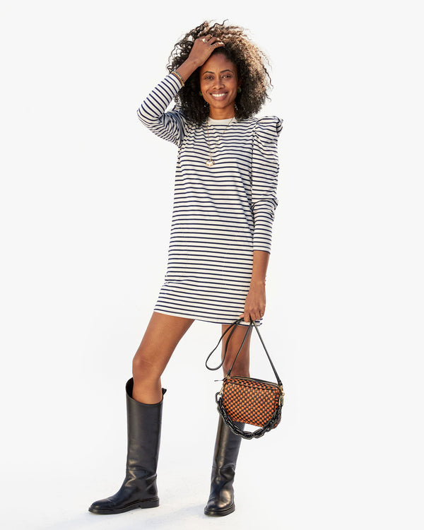 Mecca wearing the Le Puff Dress in Navy & Cream Stripe with riding boots. she's holding the midi sac in her left hand