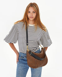 Aurelia wearing the Black & Natural Woven Checker Moyen Messenger crossbody with her hands on her hips