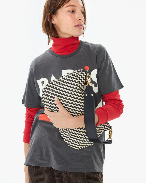 Zoe holding the Black & Cream Woven Zig Zag Moyen Messenger in front of her chest