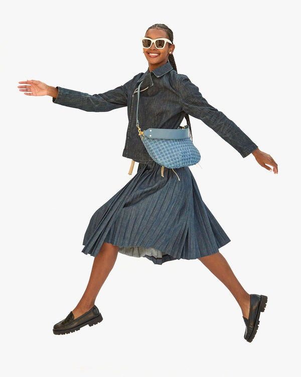 jordan jumping up in the air in a pleated skirt and a denim moto jacket with the Jean Similaire Woven Checker Moyen Messenger worn crossbody