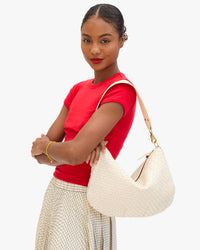 Model carrying the Cream Woven Checker Moyen Messenger as a shoulder bag.