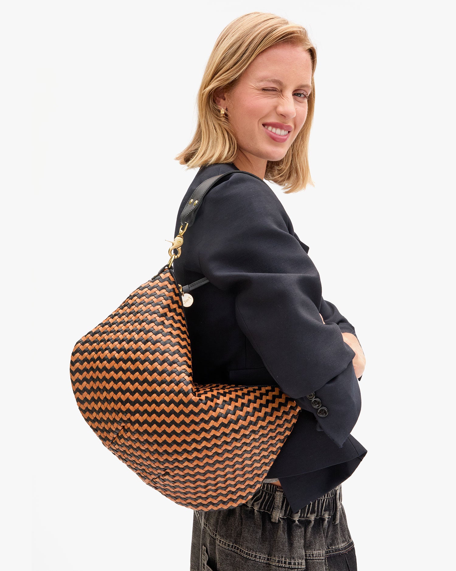 Model carrying the Black/ Natural Woven Zig-Zag Moyen Messenger as a shoulder bag.